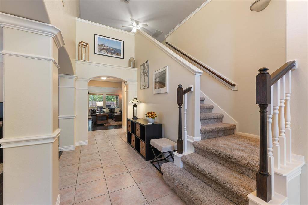 This inviting interior space features a staircase leading to the upper level. The tiled foyer opens into a well-lit living area through an elegant archway.