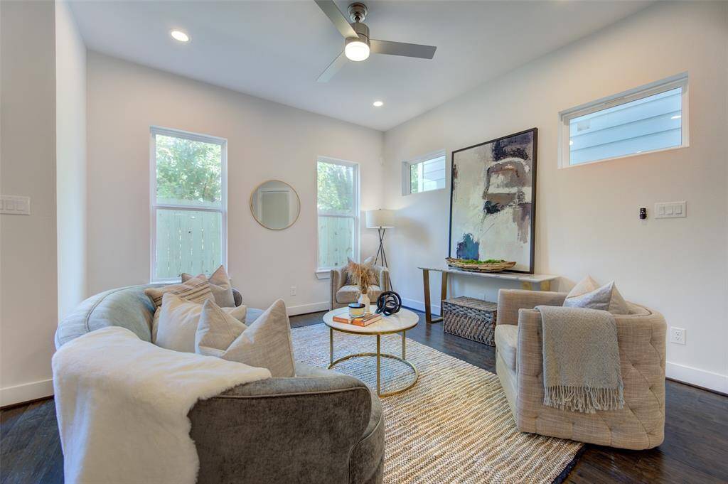 The living room is designed for comfort and style, featuring modern furnishings, high ceilings, and large windows that fill the space with natural light. The neutral color palette and tasteful decor create a serene and welcoming environment, perfect for unwinding after a long day or entertaining guests.