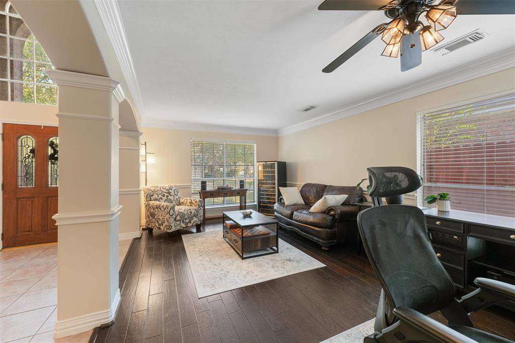 This is a well-lit, spacious room featuring  hardwood floors,  suitable for both relaxation and work.