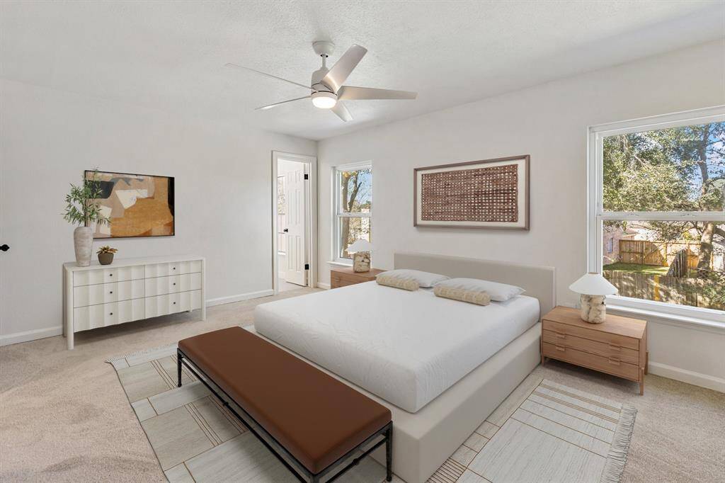 Bright and spacious primary bedroom featuring large windows for natural light and a ceiling fan, ideal for relaxation. (virtually staged)