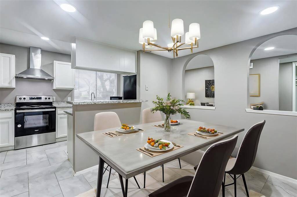 The sleek kitchen boasts modern updates with granite countertops, stainless steel appliances, and white cabinetry. A raised breakfast bar overlooks the open living area, making it easy to entertain or share meals. Bright recessed lighting ensures the space feels light and welcoming, while the open layout ties the kitchen seamlessly to the rest of the home.