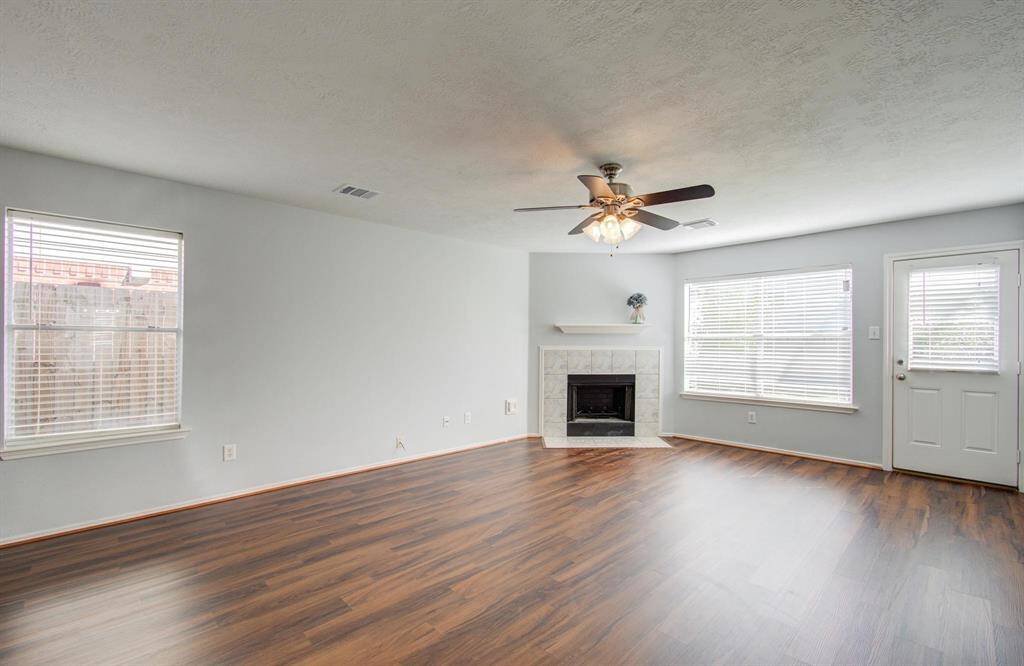 Another view of living room with plenty of natural light. Features a cozy fireplace and a door leading to back yard. Neutral walls provide a modern, clean look.