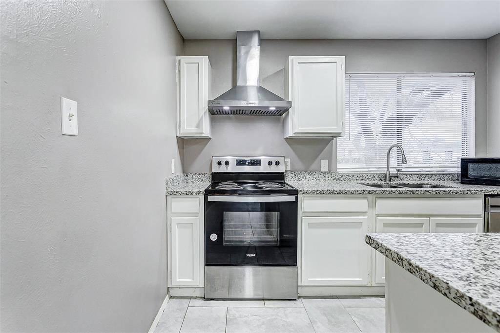 The sleek kitchen boasts modern updates with granite countertops, stainless steel appliances, and white cabinetry. A raised breakfast bar overlooks the open living area, making it easy to entertain or share meals. Bright recessed lighting ensures the space feels light and welcoming, while the open layout ties the kitchen seamlessly to the rest of the home.