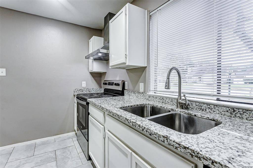 A closer look at the kitchen showcases its practical layout and attention to detail. Dual stainless steel sinks under a large window allow for plenty of natural light and a serene view while cooking or cleaning. The granite countertops stretch throughout the space, blending beauty and function seamlessly.