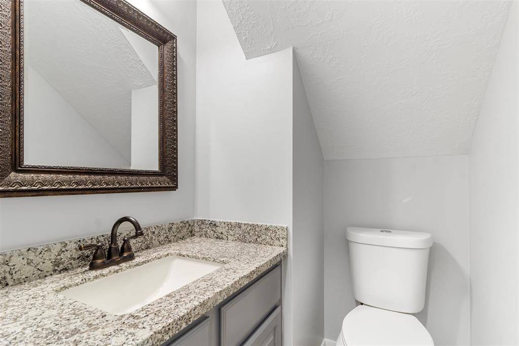 This is a compact, modern bathroom with a granite countertop, undermount sink, and elegant framed mirror. The neutral color palette and efficient layout make it a practical choice for a small space.