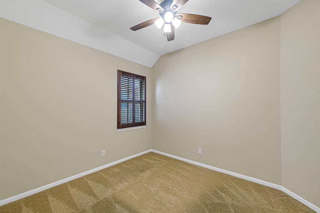 Another spacious secondary bedroom with ceiling fan and shutters.