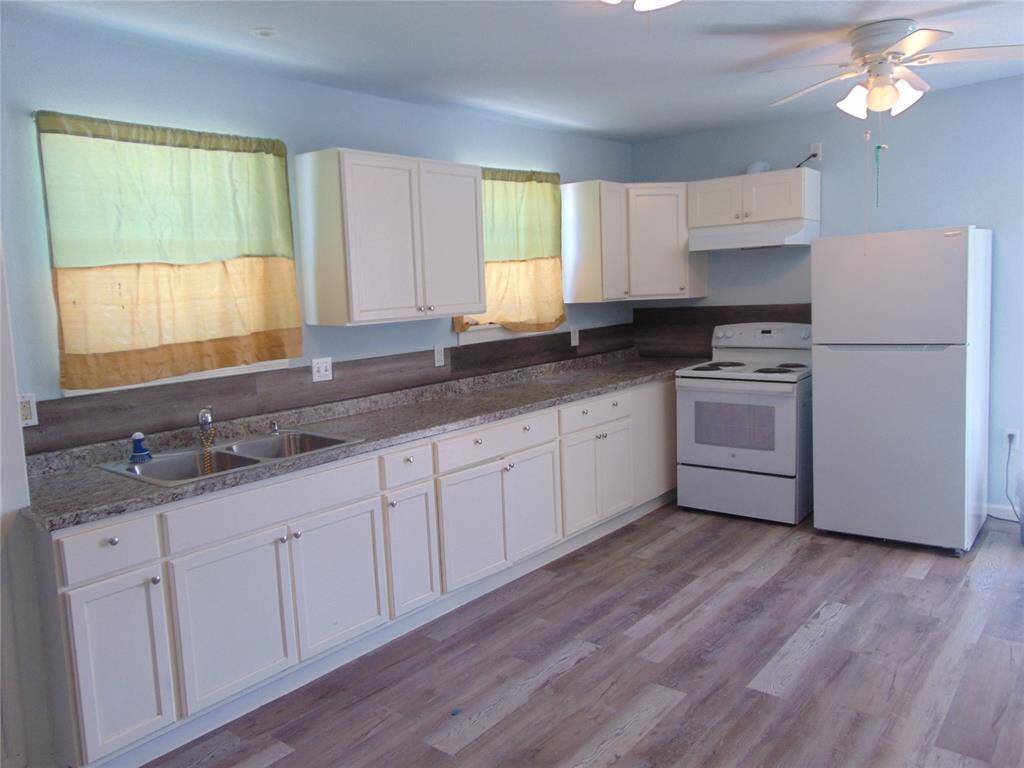 This room features light blue walls and wood-look flooring, creating a bright and airy feel. It has an arched doorway leading to another space with warm lighting and curtains, adding character and flow to the home.