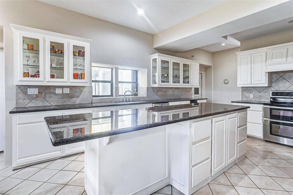 The large granite island offers ample workspace and seating, perfect for meal prep and casual dining. This space is ideal for cooking and entertaining.