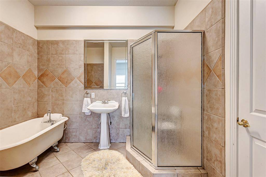 This ensuite bathroom features a classic clawfoot tub, separate shower, and walk-in closet.