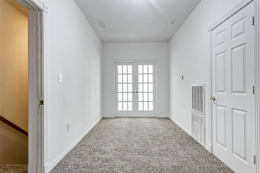 Upstairs, accessible by elevator or stairs, is a versatile flex space with elegant French doors leading to the primary suite.