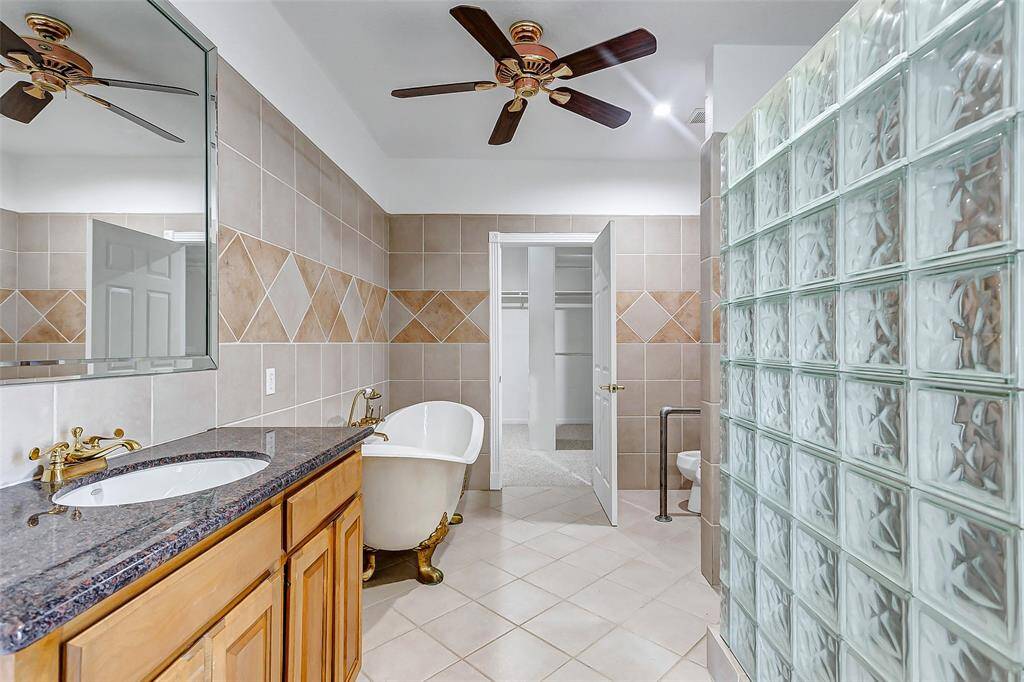 The spacious ensuite with a large window with natural light, dual vanities, a walk-in shower, a separate tub for relaxation, and a ceiling fan for comfort.