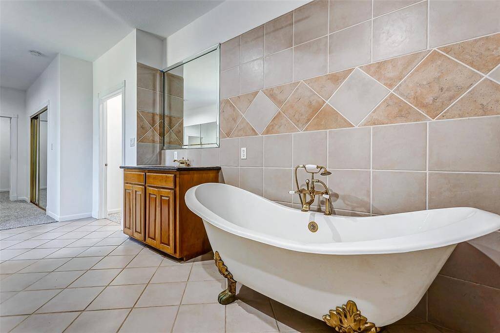 This charming clawfoot tub with gold accents serves as the centerpiece of the ensuite bathroom, combining timeless style with functionality.
