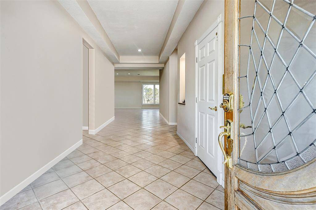 Bright foyer with neutral tile and a stylish recessed ceiling. The glass front door opens to a welcoming, light-filled open layout.