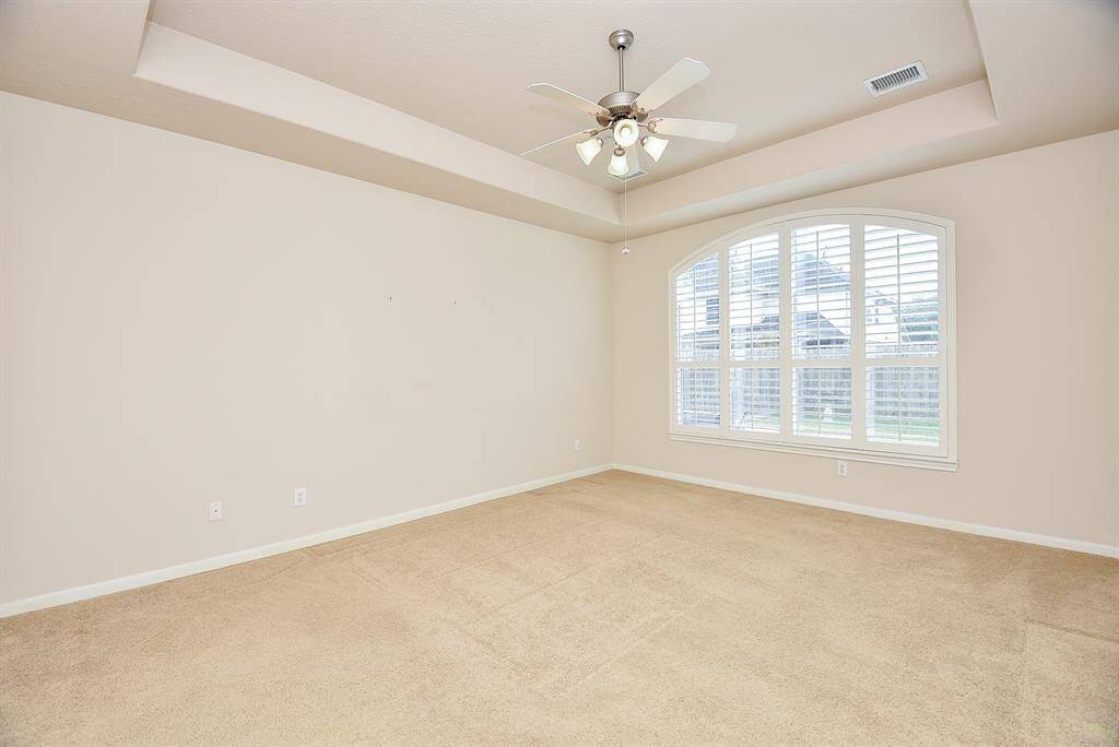 The elegance of a tray ceiling provides instant intimacy in your divine carpeted primary suite, with a charming arched window.
