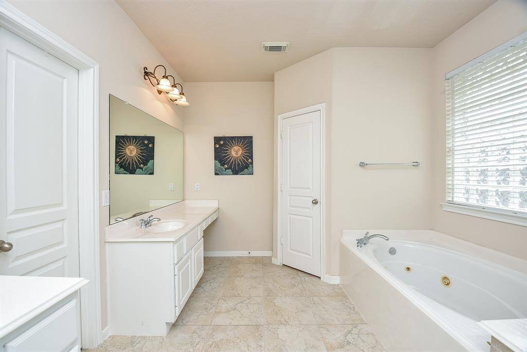 What a bright, open, completely welcoming primary ensuite bath! Dual/separate sinks/vanity offer white counter tops and abundant cabinetry, complemented by soothing relaxing vanilla tones on walls and tile flooring.