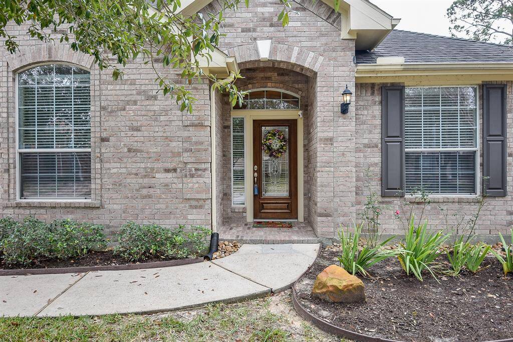 Lush planting beds line the trim walkway to the brick lined covered front entrance.