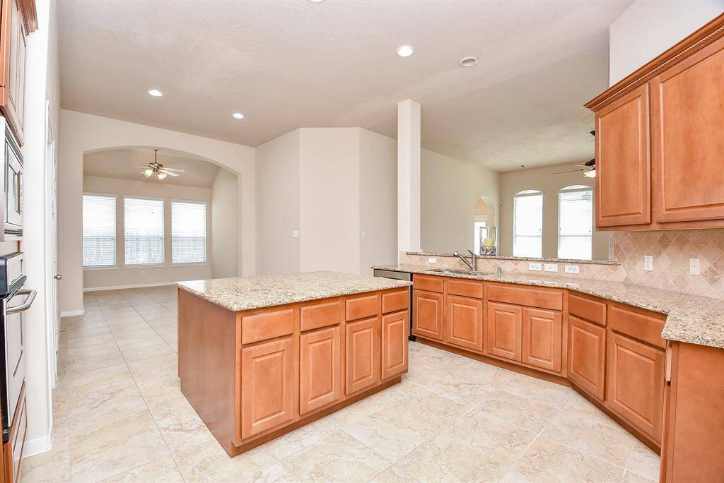 Warm, amber toned cabinetry offers tremendous storage, up and down, in this wide open, airy chef's kitchen.