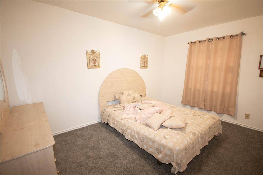 Cozy second bedroom with natural light, neutral tones, and ample space for relaxation.