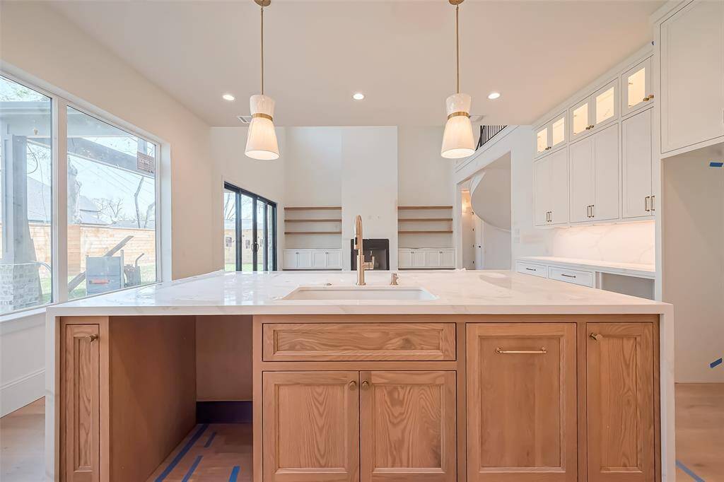 Custom built cabinetry at kitchen complemented by a stunning white oak island with a waterfall edge and matching white oak vent hood for seamless style. Photos as of 03/20/2025.