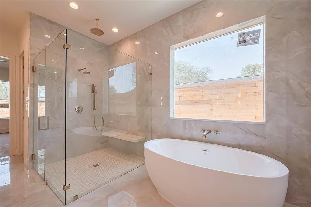 Primary Bathroom Lavish floor-to-ceiling tile for a spa-like ambiance. Photos as of 03/20/2025.
