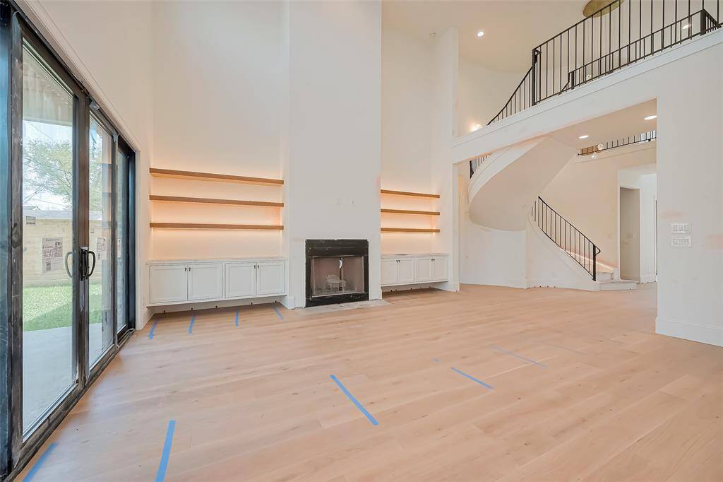 Stunning Open-Concept Living Room with beautiful real burning  fireplace and limestone mantle & complemented by white oak floating shelves with hidden LED lighting. Photos as of 03/20/2025.