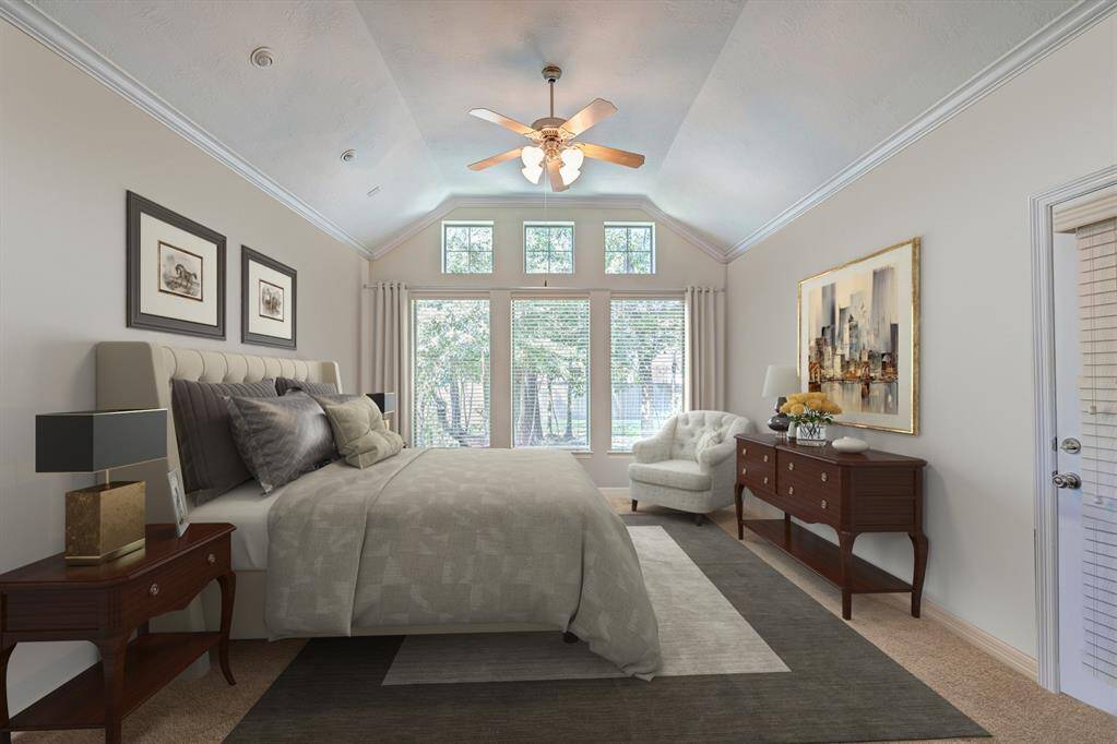 The first floor primary suite is in its own section of the house. Raised ceilings, fireplace, and a door to the patio. Note the individual reading lights above the bed. Photo is virtually furnished.