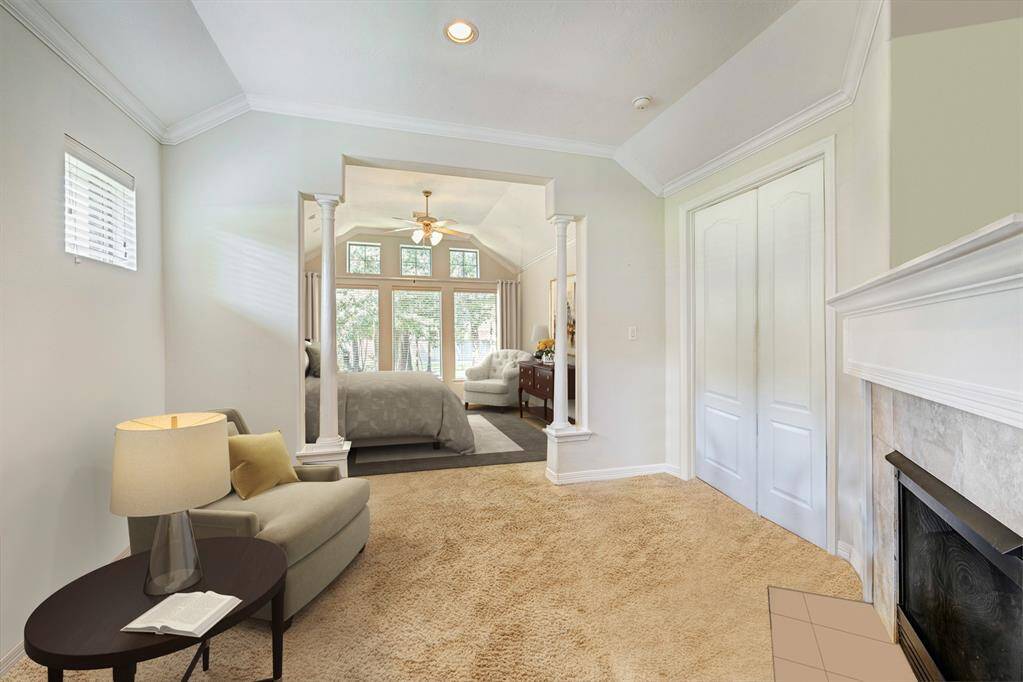 Primary seating area includes a gas log fireplace. The bedroom area is framed by columns. Photo is virtually furnished.
