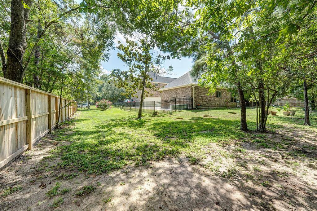 The yard continues around the side with more green space. A wrought iron fence separates the yard from the motor court for safety.