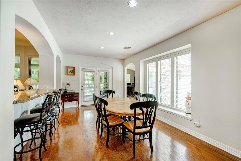 An eat-in bar separates the family room from the generous sized breakfast area. A second staircase is to the right of the photo.
