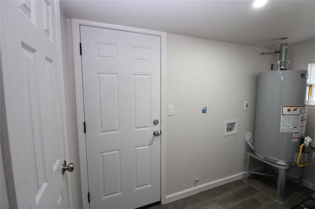 Utility room with a water heater, washer/dryer hookups, and access to the backyard.