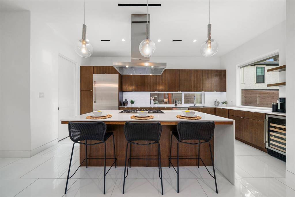 The waterfall island with built-in gas range acts as a central focal point in the kitchen.