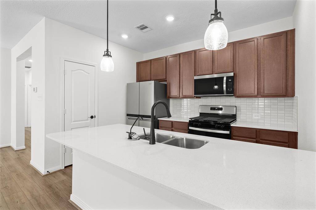 Additional view of this stunning kitchen! Featuring stained cabinets, silestone countertops, modern backsplash, stainless steel appliances, recessed lighting, and custom paint.