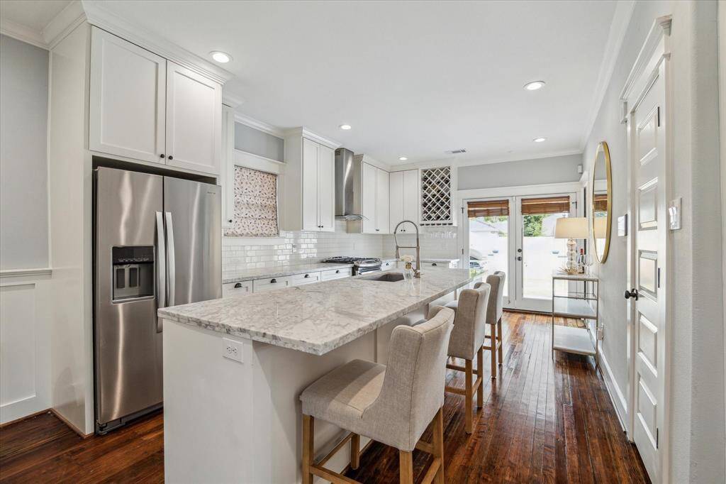 The well-appointed kitchen offers an oversized island with breakfast bar, marble counters, shaker style cabinets, SS appliances, spacious pantry, and wine storage.