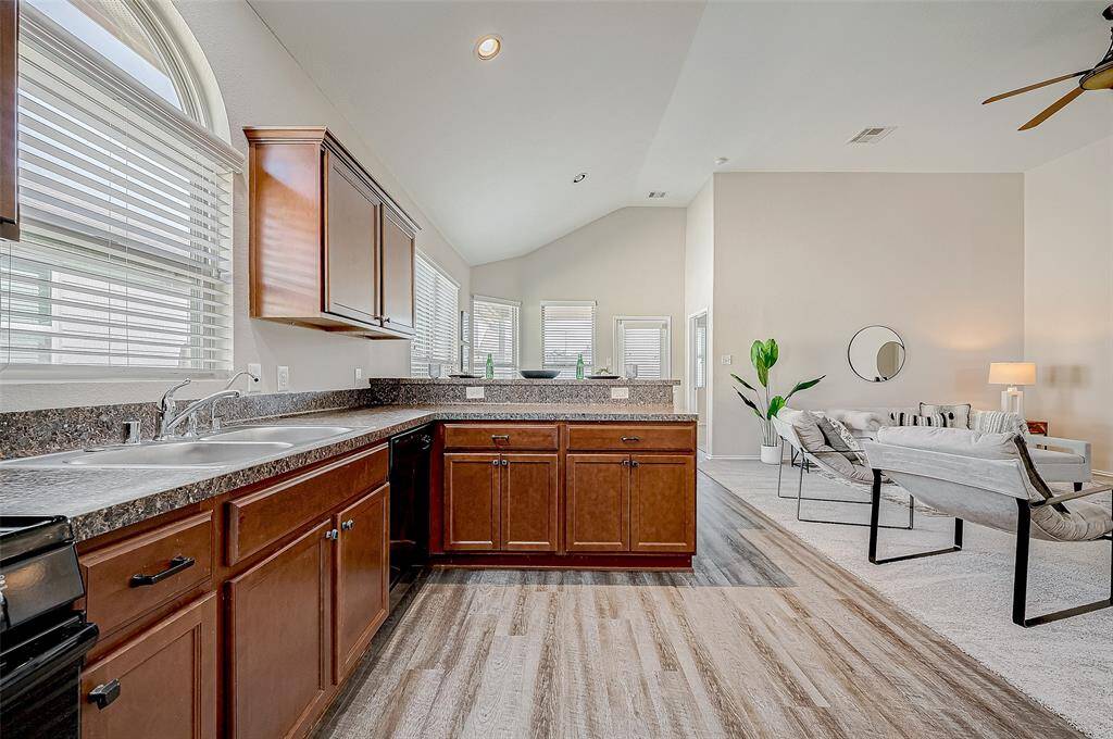 The kitchen seamlessly connects to the living area, offering an open and airy layout perfect for entertaining. Ample counter space, a double sink, and large windows provide functionality and natural light. The warm cabinetry complements the modern design, making it both stylish and practical for everyday living.