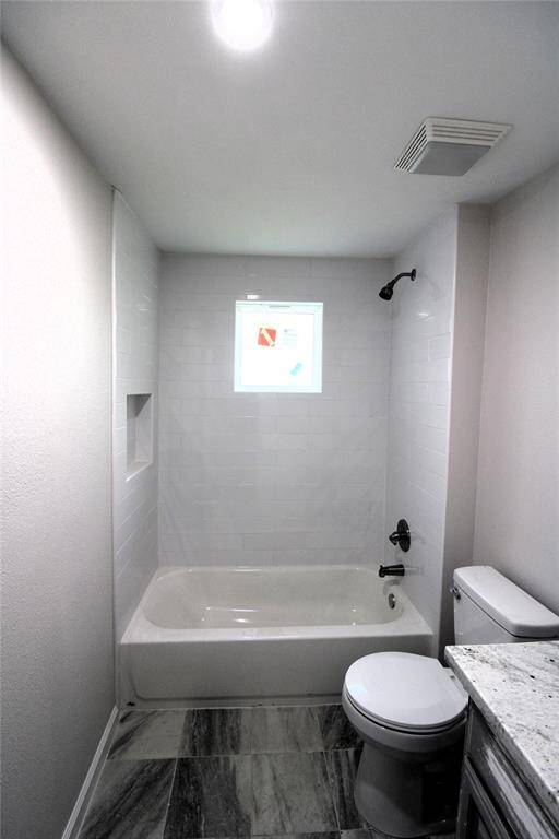 This room features neutral walls, a ceiling fan, and ample natural light from windows. It has a modern look, bedroom or office space. It also includes a closet
