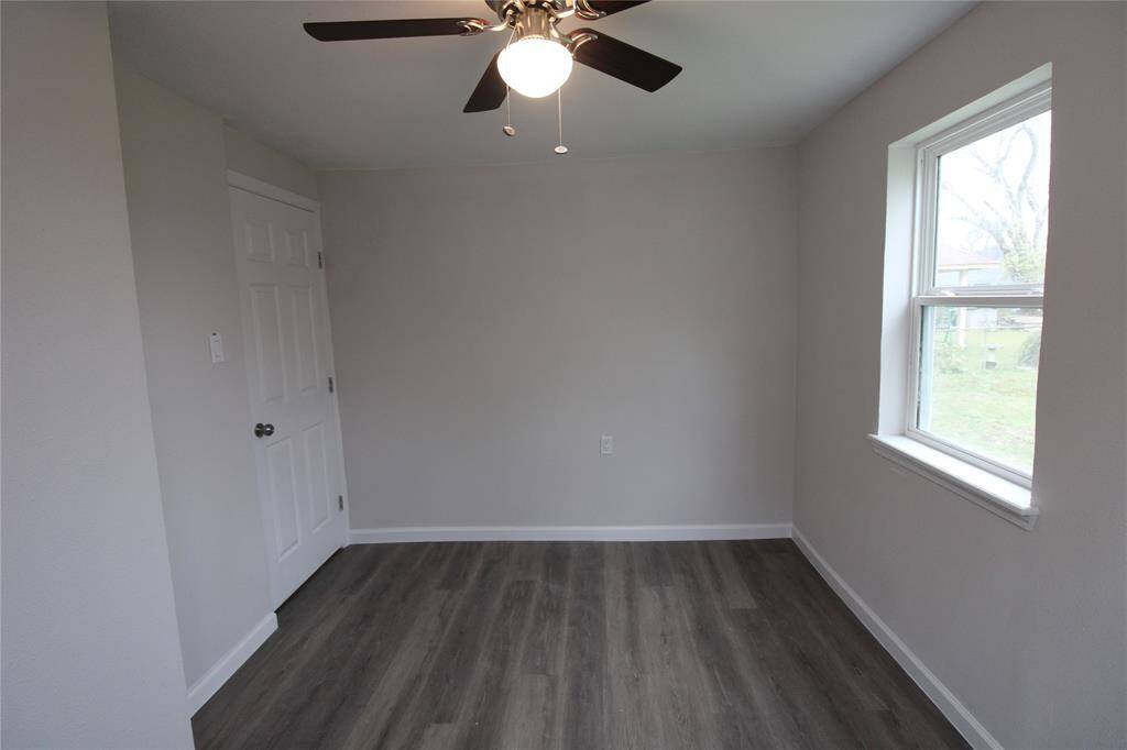 This cozy room features light gray walls, a ceiling fan, laminate flooring, and ample natural light from two windows. It also includes a closet.