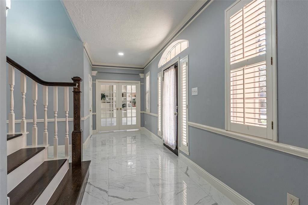 The entrance open to a well-organized home-office, complete with built-in shelves; plantation shutters enhance its charm and character.