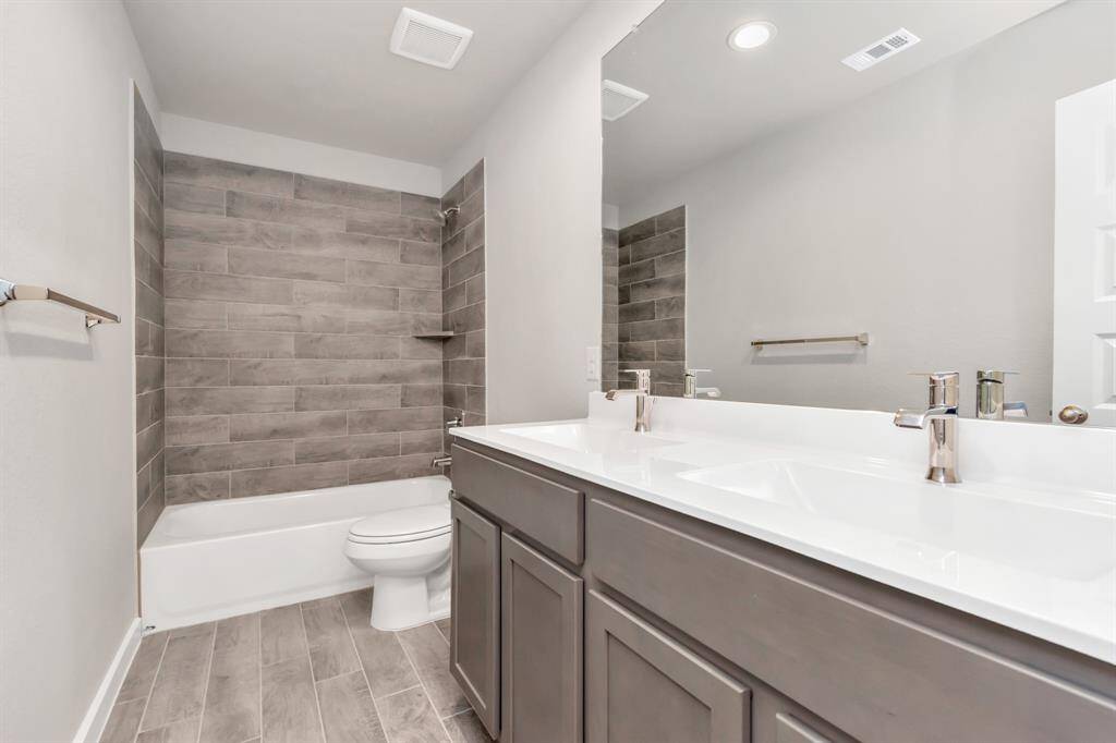 Experience sophistication in the secondary bathroom, where tile flooring complements a bath/shower combo with tile surround. Dark wood cabinets complete with a beautiful light countertop, enhances the space for a truly inviting ambiance. Sample photo of completed home with similar floor plan. As-built interior colors and selections may vary.