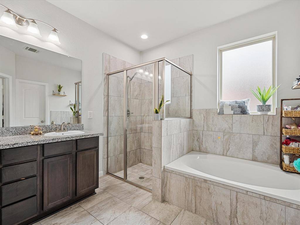 This primary modern bathroom features a spacious walk-in shower, a large soaking tub, and elegant tile work.