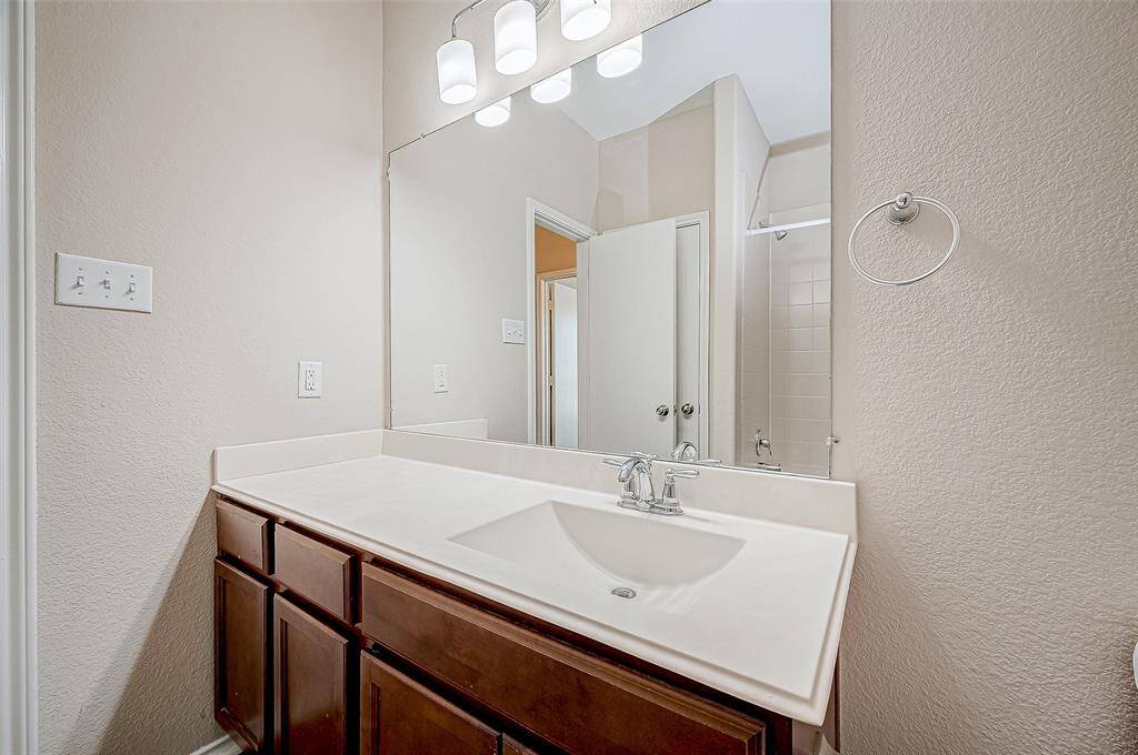 This secondary bathroom highlights a sleek, modern sink paired with a stylish chrome faucet, set against a spacious vanity. The large mirror and contemporary lighting add brightness, creating an inviting and functional space.