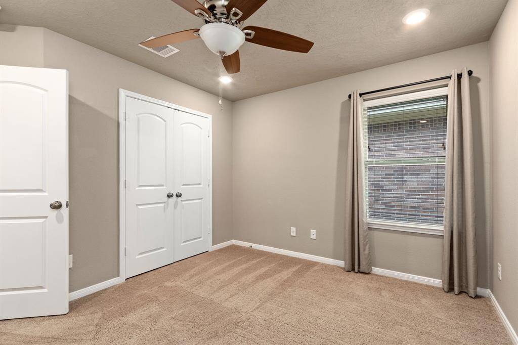 Secondary bedroom features recessed lighting, a ceiling fan, neutral wall color, and a large window.