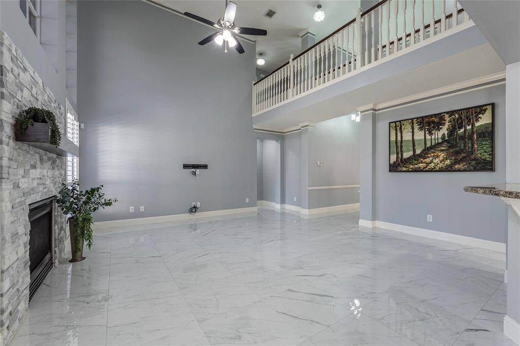 This is a spacious, open-concept living area including a view into a modern kitchen with stainless steel appliances and a casual dining area.