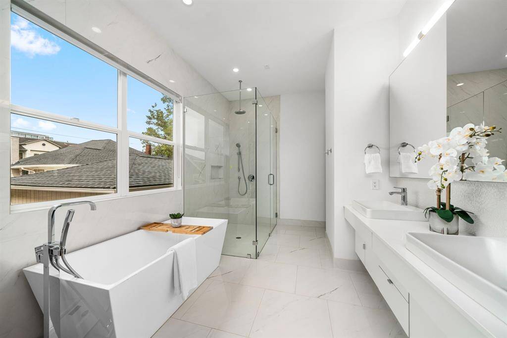 Great natural light continues into the primary bathroom, with neutral tile elements that continue up the wall to the left of the tub and shower create a true spa-like oasis.