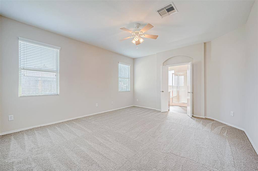 This bright and airy primary bedroom boasts ample natural light streaming through its two large windows. The neutral carpet and wall tones create a tranquil retreat, while the double doors lead seamlessly into the en-suite bathroom for added convenience and privacy.