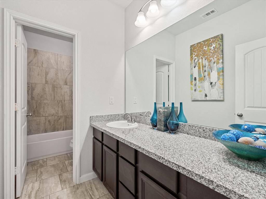 Full secondary bath with a tiled tub/shower combo and granite countertops!