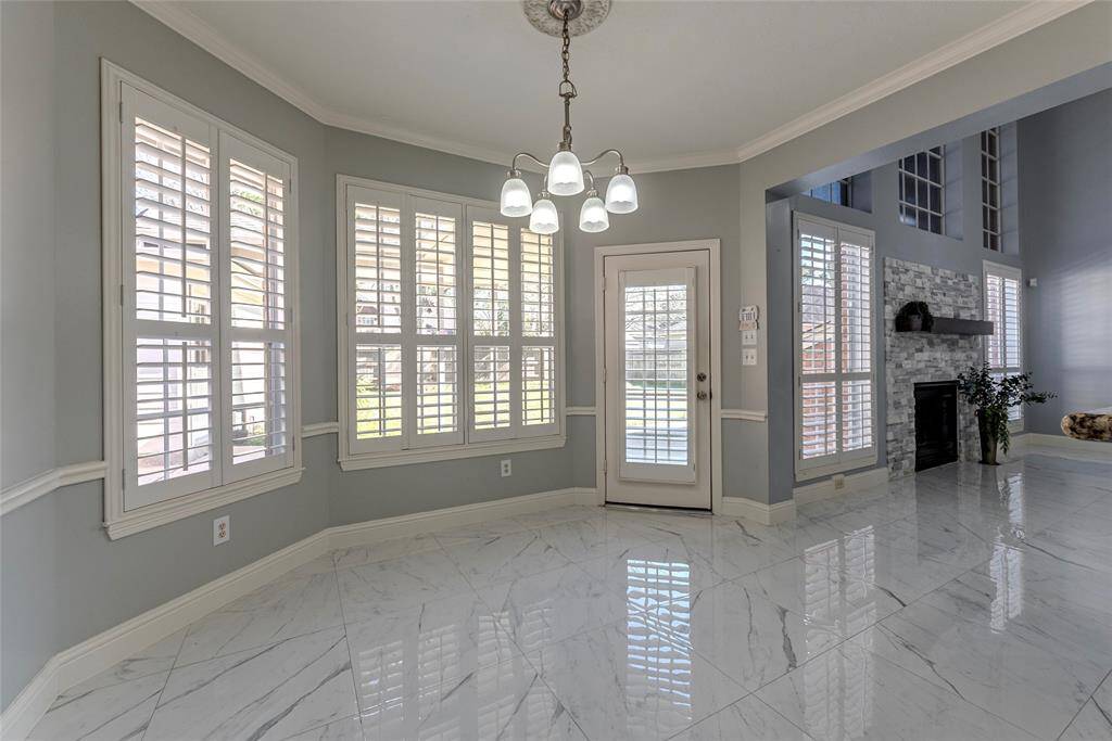 Light and bright breakfast area featuring chair-rail molding, crown molding, porcelain tile flooring and Plantation shutters.