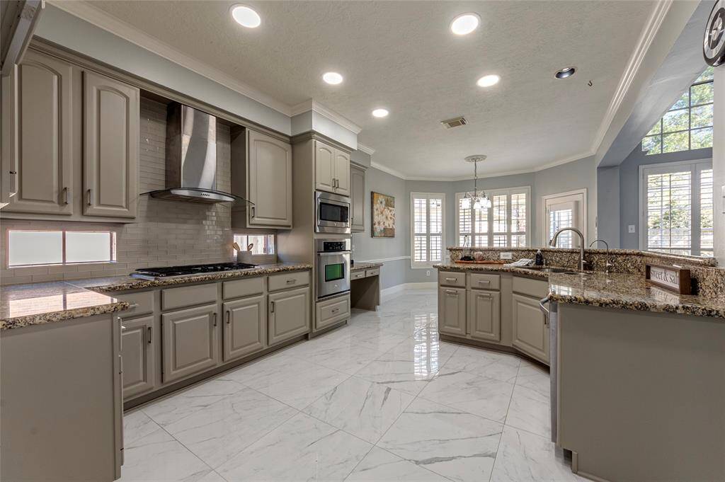 Beautiful open-concept kitchen featuring gorgeous granite counter tops, subway ceramic tile backsplash, crown molding and porcelain tile flooring.