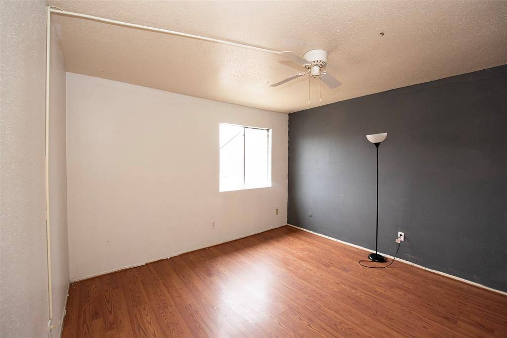 Primary bedroom with laminate wood floors and great accent wall.