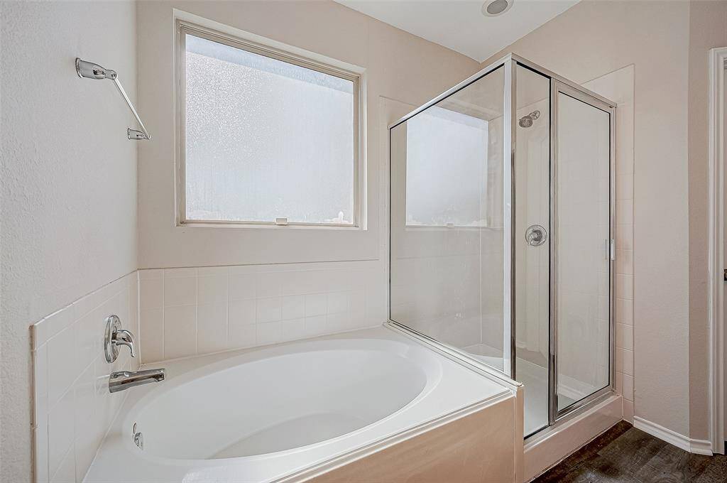 The bathroom features a relaxing soaking tub nestled beneath a frosted window, allowing natural light to fill the space while maintaining privacy.