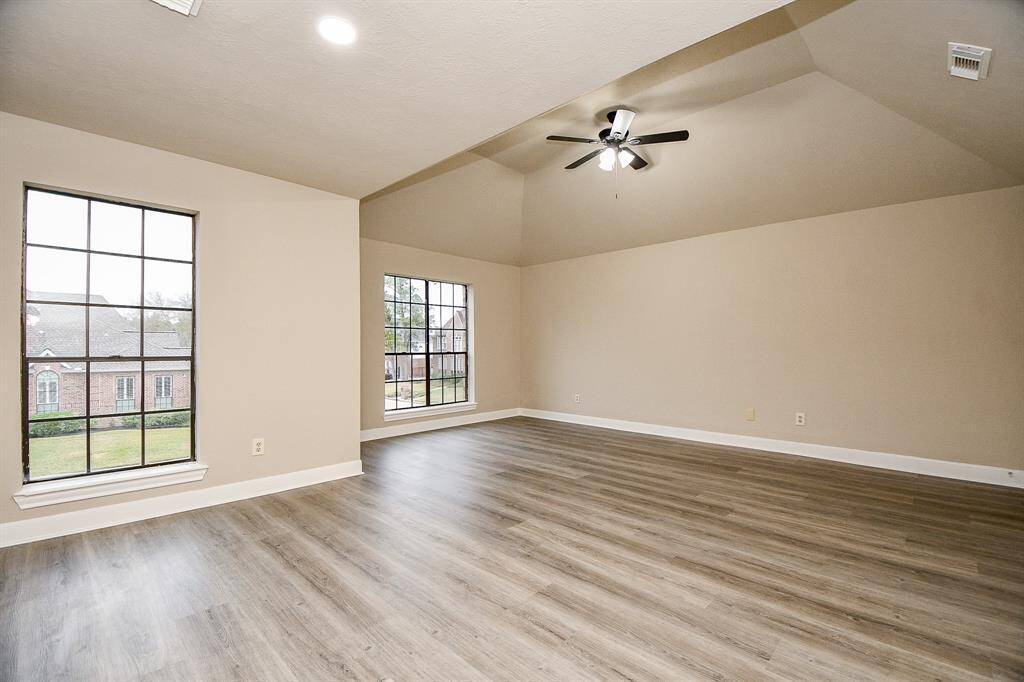 This captivating view of the game room emphasizes its expansive floor plan and abundant natural light streaming through a wall of windows. A glimpse of a private bedroom tucked away off the main space further highlights the versatility of this impressive entertainment area.